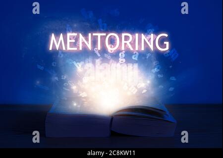 Livre ouvert avec inscription de mentorat. La lumière vient du livre ouvert avec le mot mentorat. Banque D'Images