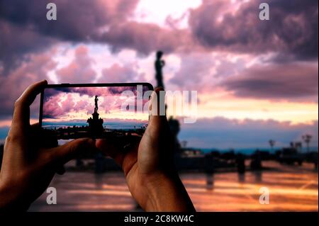 Touriste prenant une photo de la réplique de la statue du David de Michel-Ange sur la place Michel-Ange pendant le coucher du soleil à Florence, Italie. Homme tenant le téléphone et prenant p Banque D'Images