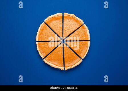 Posez-le sur un fond bleu foncé avec une tarte à la citrouille maison. Tarte à la citrouille coupée en huit morceaux. Dessert maison de Thanksgiving. Banque D'Images