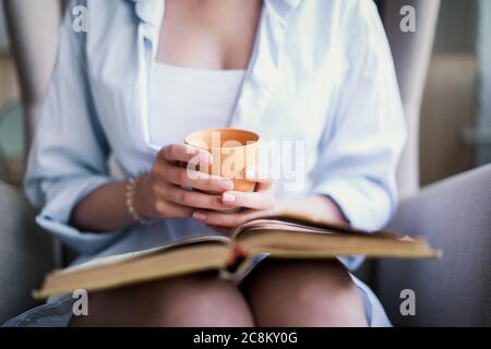Belle fille lisant un livre à la maison. Loisirs en intérieur Banque D'Images