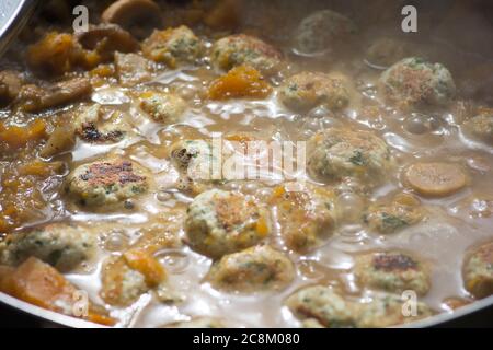 Vue rapprochée des boulettes de dinde cuites dans une soupe de légumes bouillonnante Banque D'Images