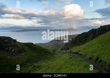 Un arc-en-ciel au-dessus des montagnes au loin. Sentier de randonnée jusqu'au majestueux sommet rocheux du Old Man of Storr. Banque D'Images