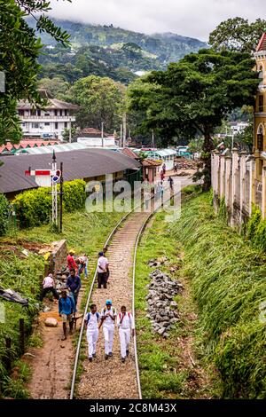 Les étudiants marchent le long des voies ferrées à l'extérieur de la gare de Kandy au Sri Lanka Banque D'Images