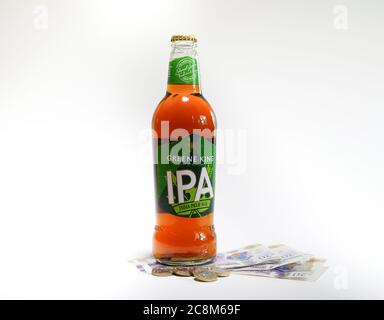 Gros plan bouteille de bière IPA isolée sur pile de cash au Royaume-Uni, argent avec fond blanc. Concept bière argent, boire de l'argent, allocation de dépense. Banque D'Images