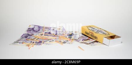 Notes de vingt livres sur fond blanc couvertes de matchs sans heurt et boîte d'allumettes ouverte. Concept ayant de l'argent à brûler, plus que suffisant, extravagance. Banque D'Images