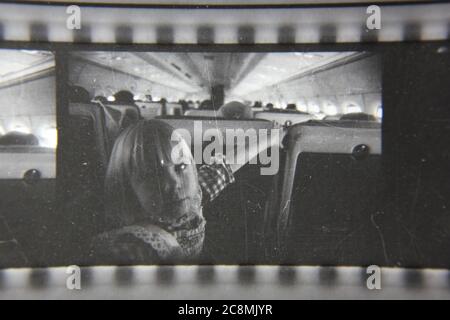 Belle photographie en noir et blanc vintage des années 1970 d'une jeune fille voyageant dans un avion. Banque D'Images