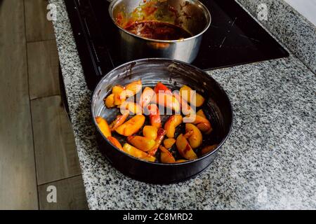 De délicieuses pommes caramélisées prises dans une casserole sur un comptoir pour une recette de gâteau préparée sur une cuisinière à induction Banque D'Images