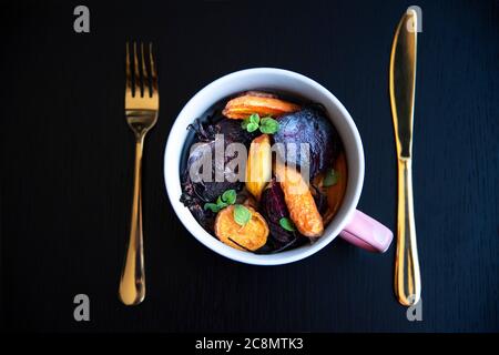 Émincé et rôti de légumes avant de les mettre au four. Carottes, pommes de terre, patates douces, betteraves, kohlrabi, romarin, ail, hyssop Banque D'Images