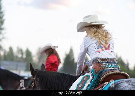 Miss Last chance Rodeo Queen Cassie Turner (à droite) et Darby Rodeo Queen Abby Riska se sont inclinés la tête pendant un moment de silence au Kootenai River Stampede à Libby, Montana, le vendredi 24 juillet 2020. Le rodéo annuel a été organisé avec des mesures de sécurité supplémentaires en place en raison de la montée des cas de COVID-19 dans l'État. Banque D'Images