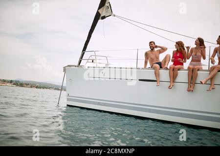 Des amis se rafraîchillant sur le pont d'un yacht par une journée ensoleillée Banque D'Images