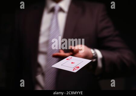 Homme dans un costume d'affaires cache rouge ace carte à jouer. Banque D'Images