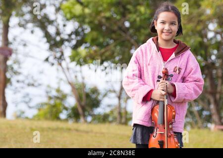 Un portrait d'une fille asiatique et de son violon dans la prairie du matin lors d'un séjour sur la montagne Banque D'Images