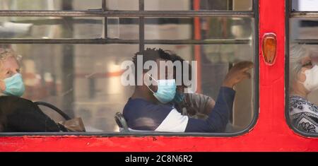 Belgrade, Serbie - 16 juillet 2020 : jeune homme noir portant un masque chirurgical tout en étant assis et en montant sur un siège de fenêtre d'un tramway Banque D'Images
