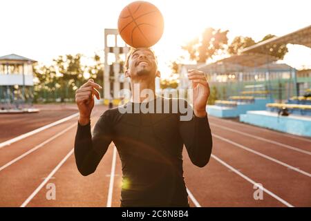 Photo de jeunes fortement positive de l'Afrique de l'homme à l'extérieur du stade de sports jouer au basket-ball. Banque D'Images