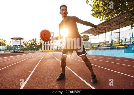 Image d'une Afrique forte beau jeune homme sportif au stade à l'extérieur jouer au basket-ball. Banque D'Images