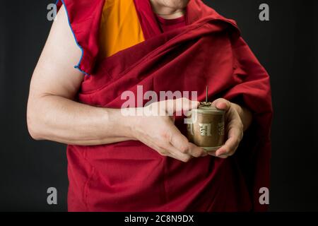 Le moine tient un tambour de prière dans sa main. Portrait d'un moine bouddhiste en vêtements rouges. Banque D'Images