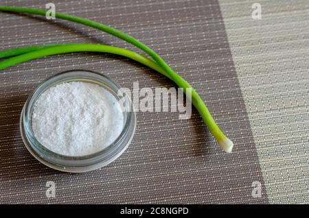 Saupoudreuse et oignons de laitue. Ciboulette crue sur la table de cuisine. Nourriture biologique simple. Mise au point sélective. Banque D'Images