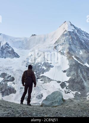 Vue arrière d'un touriste regardant l'une des plus belles montagnes des Alpes suisses - Ober Gabelhorn, qui un côté est couvert de neige. Trekking, randonnée en montagne, homme atteignant le sommet. Banque D'Images