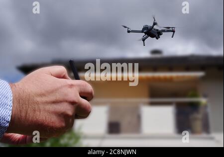 Drone dans l'air inspectant le toit au-dessus de la maison. Gros plan du drone et du toit. Banque D'Images