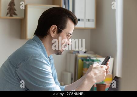 Concentré homme caucasien textant sur téléphone portable moderne Banque D'Images