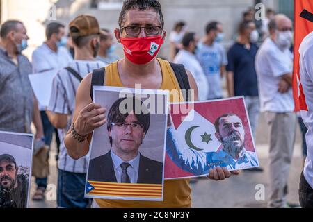 Barcelone, Espagne. 25 juillet 2020. Un partisan du mouvement populaire de RIF (Hirak) portant un masque est vu montrant des pancartes avec le président de la Generalitat de Catalogne Carles Puigdemont et le dirigeant et activiste de Rif Nasser Zefzafi pendant le rassemblement.sympathisants du mouvement populaire de RIF (Hirak) résidant en Catalogne rassemblés sur la place Sant Jaume à Barcelone pour commémorer la proclamation de la première république de Rif et se souvenir de leurs prisonniers politiques. Crédit : SOPA Images Limited/Alamy Live News Banque D'Images