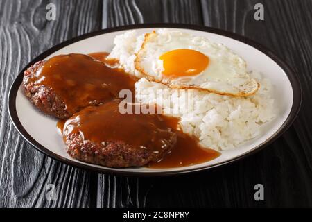 le loco moco est une cuisine hawaïenne à base de riz blanc avec une patty hamburger, un côté ensoleillé de l'œuf et de la sauce au bœuf brune sur une assiette sur la table. Banque D'Images