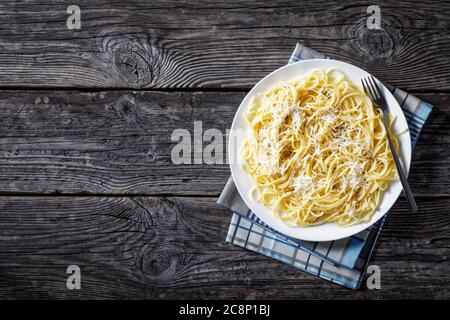 Spaghettis à la crème de fromage et saupoudrées de poivre noir sur une plaque blanche sur une vieille table en bois, belrom e pepe, la cuisine italienne, vue depuis l'ab Banque D'Images