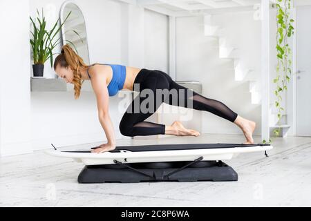 Une jeune femme qui fait un alpiniste pose sur un surset en position de planche dans un entraînement cardiovasculaire dans une salle de gym de haute clé Banque D'Images