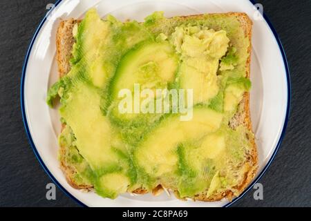 Avocat fraîchement haché sur du pain de grain entier. Un sandwich végétarien sain sur une surface en pierre texturée Banque D'Images