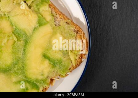 Avocat fraîchement haché sur du pain de grain entier. Un sandwich végétarien sain sur une surface en pierre texturée. CopySpace Banque D'Images