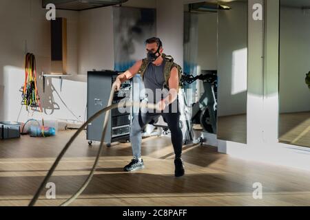 Sportif à l'entraînement de corde avec masque d'entraînement. Intérieur sur parquet en chêne avec soleil et ombre. Pour le concept de camp de démarrage. Banque D'Images