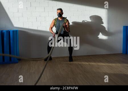 Sportif à l'entraînement de corde avec masque d'entraînement. Intérieur sur parquet en chêne avec soleil et ombre. Pour le concept de camp de démarrage. Banque D'Images