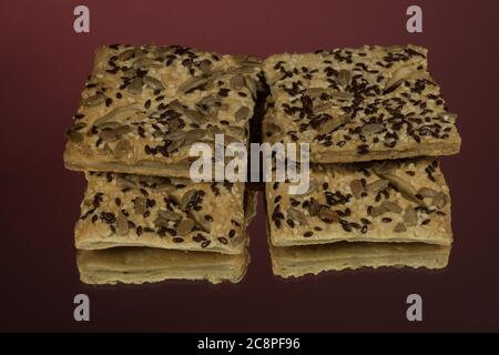 Bâtonnets de pâte feuilletée avec graines de sésame et de pavot isolées sur fond rouge Banque D'Images