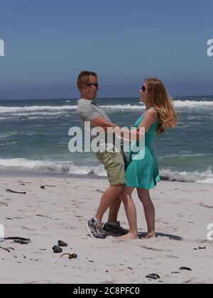 Mignon jeune couple, saut de plage de sable blanc pour la joie, heureux d'être ensemble Banque D'Images