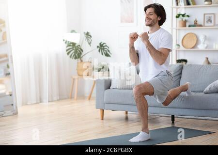 Jeune homme beau travaillant sur ses muscles à la maison Banque D'Images