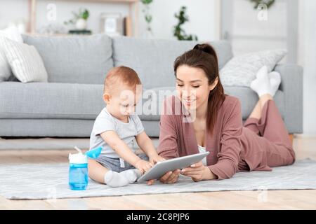 Jeune maman et son bébé fils jouant à des jeux de déelopment sur la tablette numérique Banque D'Images