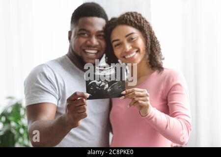 Couple enceinte souriant montrant l'image échographique de son bébé Banque D'Images