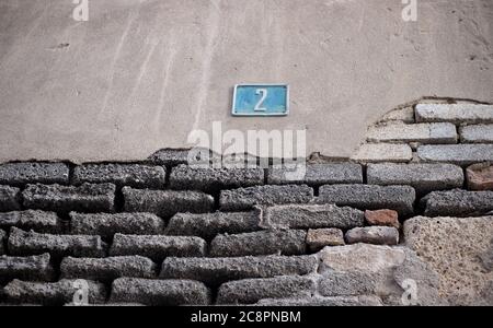 Numéro deux sur un mur grundy avec plâtre écaillé, tons subdués mur de brique image, perspective à angle bas. Banque D'Images