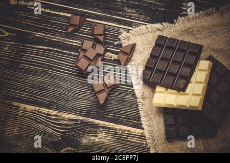 Groupe de barres de chocolat différentes couleurs. Différents types de bonbons assortis. Chocolat assorti sur fond de bois rustique Banque D'Images