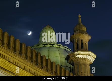 Un dôme à oignon et un minaret sur le dôme de Brighton, avec une nouvelle lune en arrière-plan. Banque D'Images