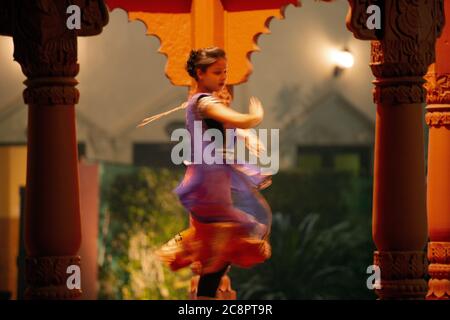 Une jeune femme effectue une danse traditionnelle dans un costume de couleur vive dans l'Inde. Banque D'Images