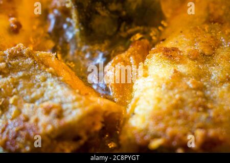 Morceaux de poisson navaga en pâte, frits dans l'huile dans une casserole. Banque D'Images