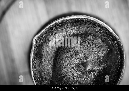 Café naturel avec mousse épaisse, brassé dans une cève de cuivre de la manière classique, sur un fond de bois, photo macro. Banque D'Images