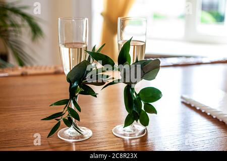 des verres de champagne sont décorés de branches vertes sur la table Banque D'Images