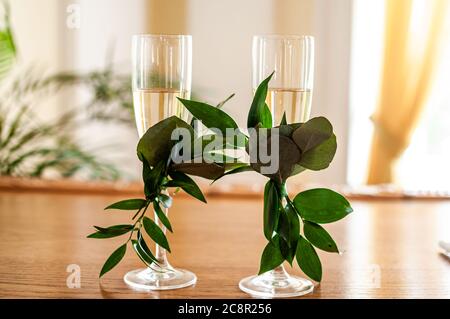 des verres de champagne sont décorés de branches vertes sur la table Banque D'Images