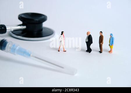 Photographie miniature conceptuelle du coronavirus pandémique – un groupe de personnes s'alignent pour un bilan de santé. Image photo Banque D'Images