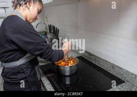 Une adolescente cuisant sur une cuisinière à induction. Processus de préparation de la tarte aux pommes Banque D'Images