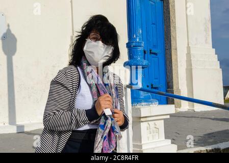 la femme mature se protège du vent devant une église portant une mascara Banque D'Images