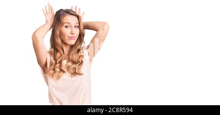 Jeune belle femme caucasienne avec cheveux blonds portant des vêtements décontractés faisant des oreilles de lapin geste avec les mains palmiers ayant l'air cynique et sceptique. pâques Banque D'Images