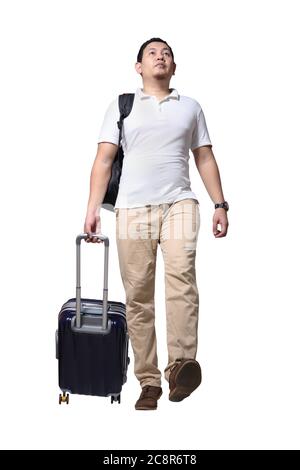 Homme asiatique voyageur marchant vers l'avant traînez sa valise à bagages, portant une chemise et un sac à dos décontractés, vue à angle bas portrait sur toute la longueur isolée sur blanc Banque D'Images